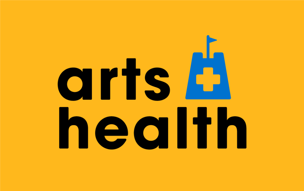 The words 'arts + health' are in black lettering on a bright yellow backdrop. The character '+' is set against a blue sandcastle with a flag on top